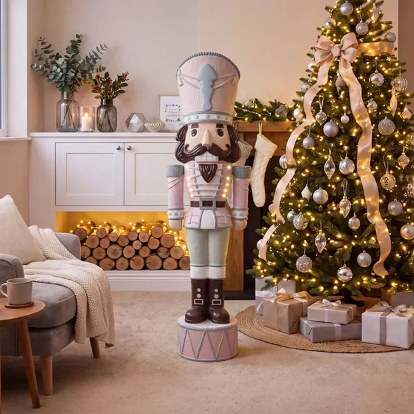 Gum Drop Swizzle Otto nutcracker in pastel pink and sage beside a Christmas tree