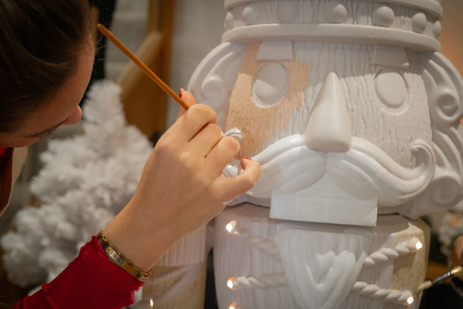 Close-up of a hand painting the face of a Paint Your Own Otto with a fine brush